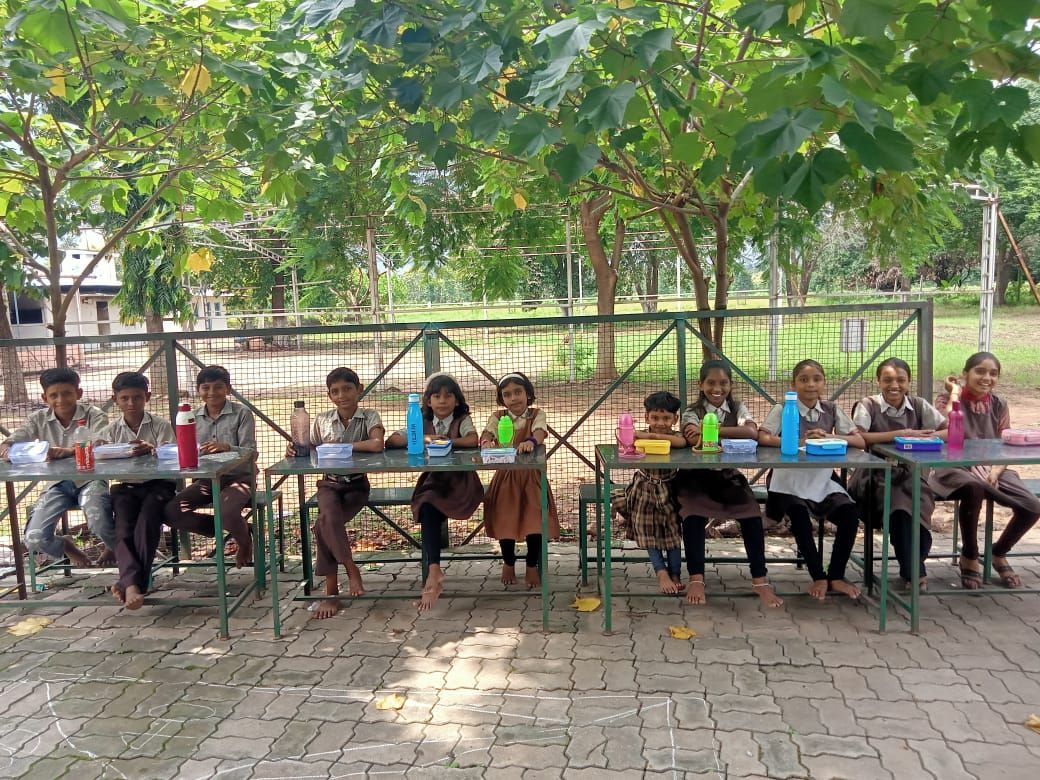 Students having lunch together under the trees