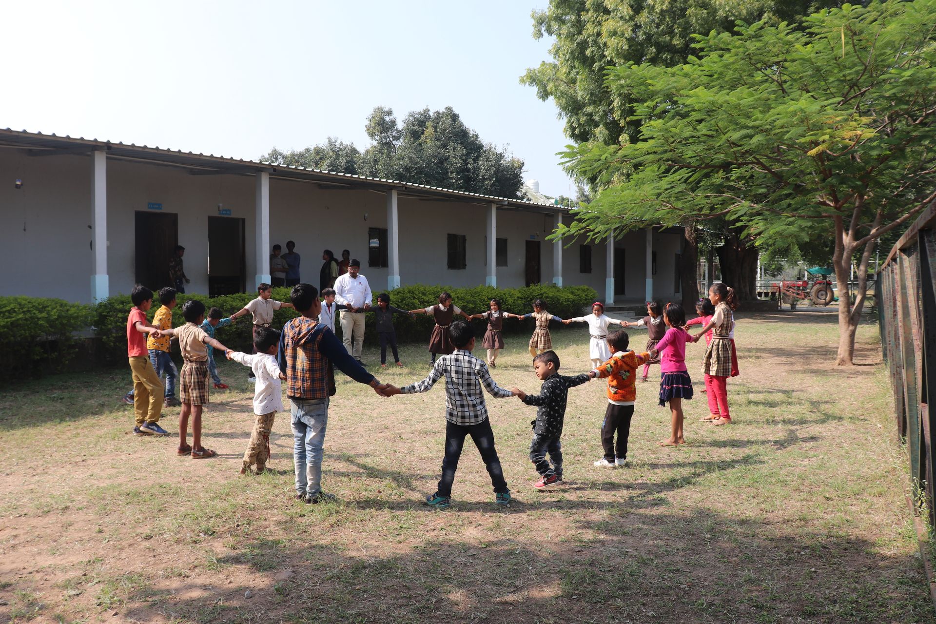 Children playing a circle game on campus